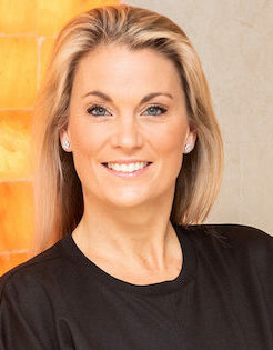 Woman in black dress in front of a himalayan salt wall