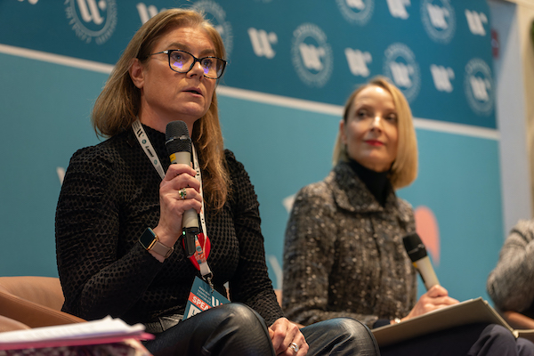 woman with microphone speaking at a conference