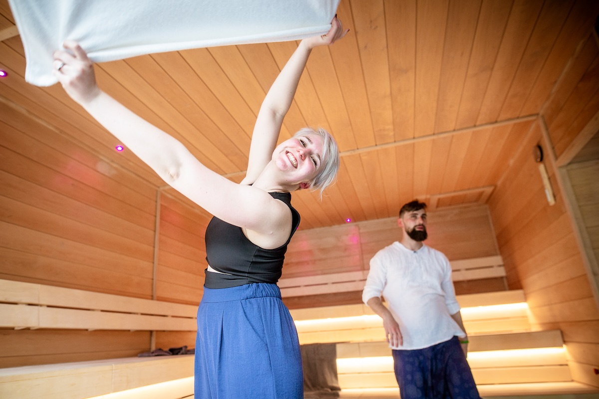 Man and woman performing sauna ritual waving towels