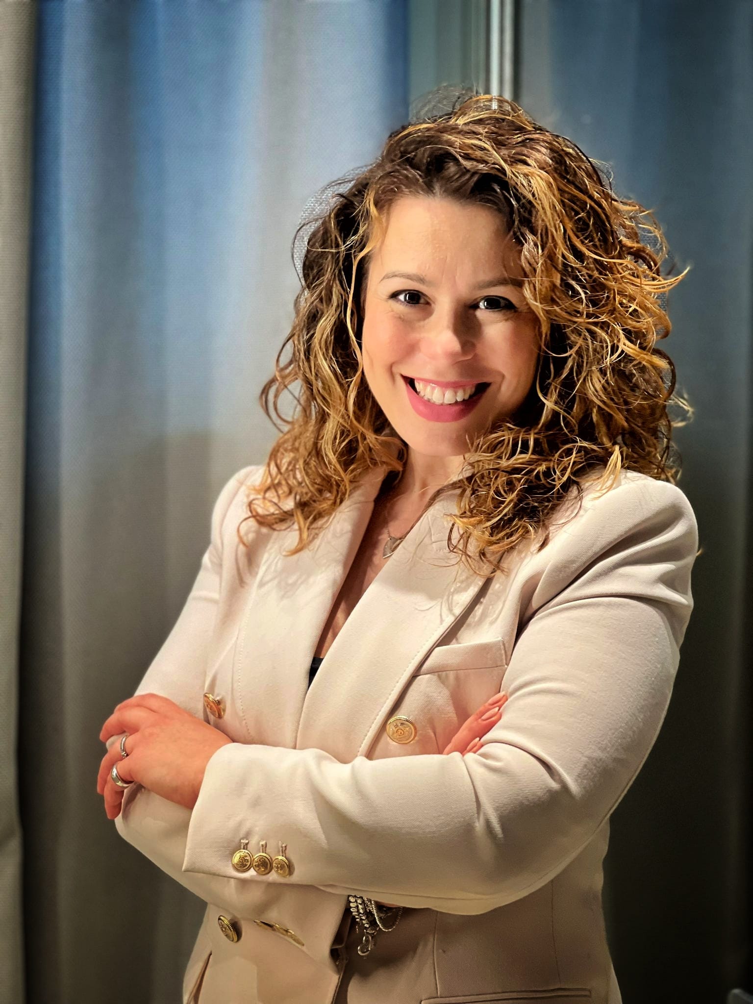Smiling woman with curly hair in beige jacket